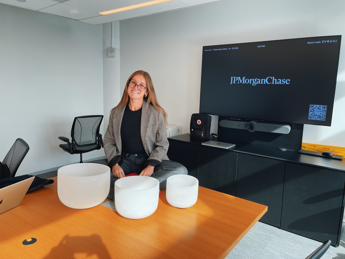 A practitioner seated behind three crystal singing bowls on a conference room table